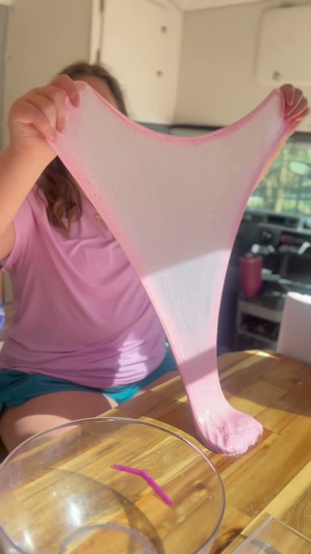 A child proudly stretching their pink slime